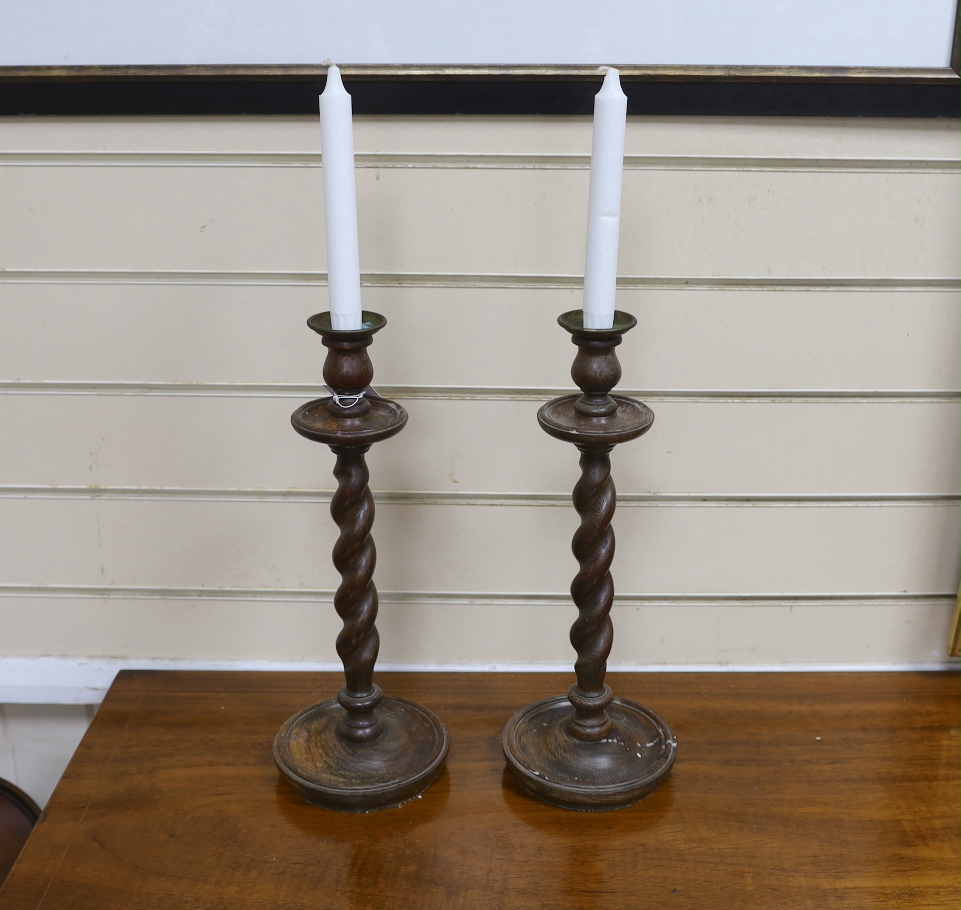 A pair of early 20th century spiral turned candlesticks with brass sconces, height 38cm
